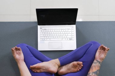İnternette yoga dersi veren genç bir kadın. Spor giyim bölümünde çalışan ya da dizüstü bilgisayarda ders çalışan bir kadın. Yüksek kalite fotoğraf