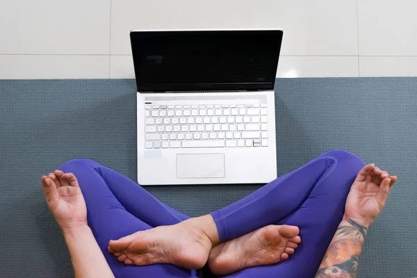 İnternette yoga dersi veren genç bir kadın. Spor giyim bölümünde çalışan ya da dizüstü bilgisayarda ders çalışan bir kadın. Yüksek kalite fotoğraf