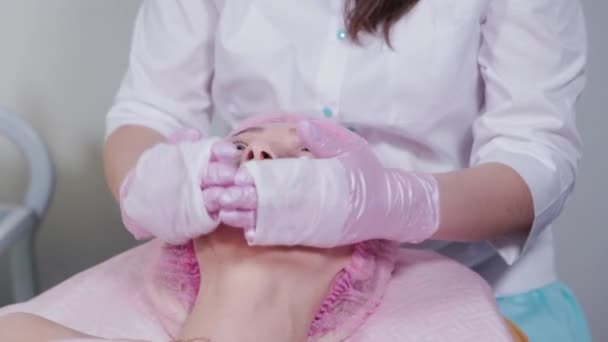 Женщина-косметолог умывается лицом клиента косметологической клиники. — стоковое видео