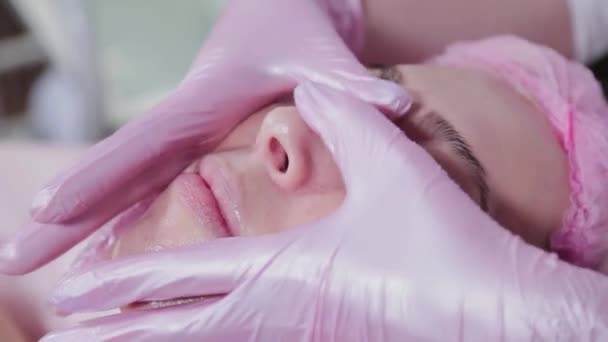Mujer esteticista frota crema en la cara de un cliente de una clínica de cosmetología. — Vídeo de stock
