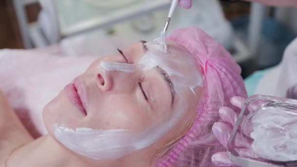 Женщина косметолог наносит крем с кистью на молодую женщину. — стоковое видео