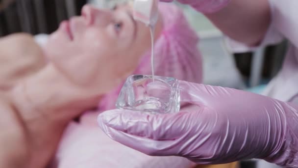 En kvinnlig kosmetolog häller en speciell kosmetisk lösning i en behållare. — Stockvideo