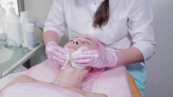 Woman beautician washes off cream from young womans face. — Stock Video