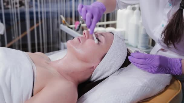 Il cosmetologo di donna applica il peeling a faccia di donne a cliente di clinica cosmetology. — Video Stock