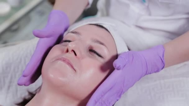 Kosmetolog kobieta masaże kobietom twarz kremem. — Wideo stockowe
