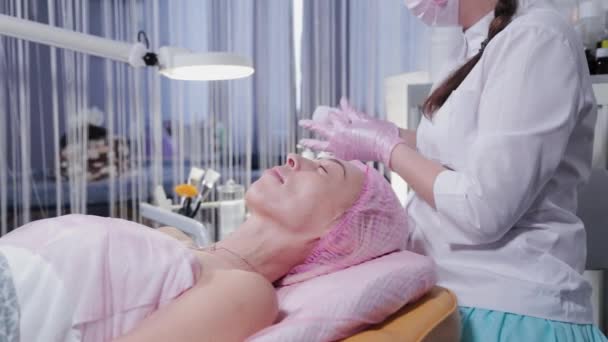 Mulher esteticista lava o rosto do cliente da clínica de cosmetologia. — Vídeo de Stock