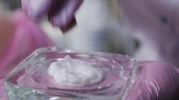 Vrouw schoonheidsspecialiste voegt een speciaal serum aan de crème. — Stockvideo