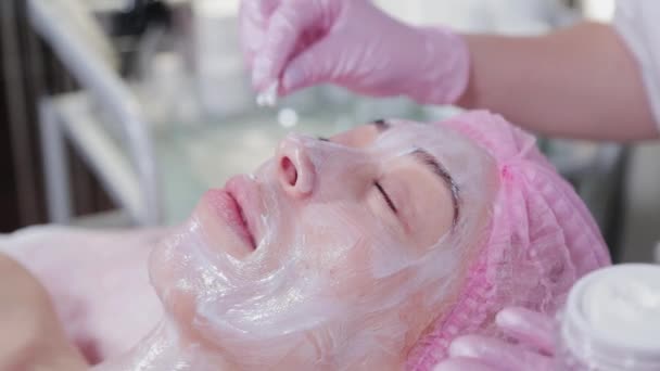 Жінка-косметолог посипає вітамін С на обличчі бавовняними бруньками . — стокове відео