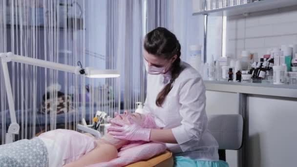 Kadın güzellik uzmanı genç bir kadına yüz masajı yapıyor.. — Stok video