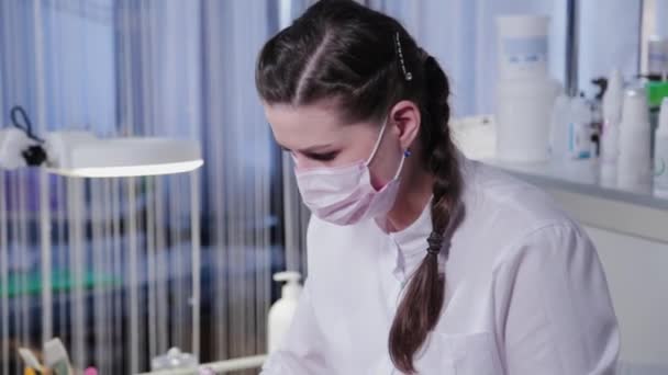 Kosmetikerin schmiert einer Patientin Creme ins Gesicht. Gesichtsmassage. — Stockvideo