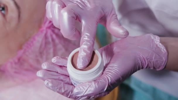 Mujer esteticista unta crema en sus dedos. — Vídeo de stock