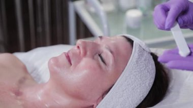 Kadın güzellik uzmanı özel bir spatulayla krema aldı..