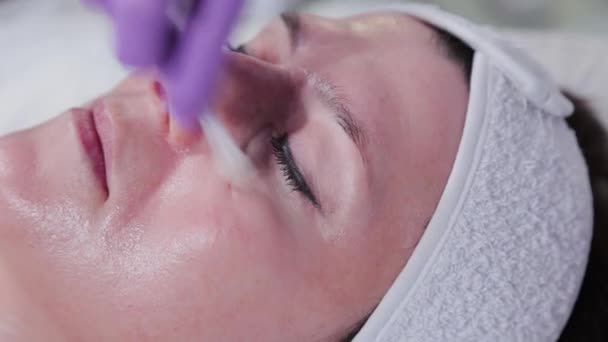 Mujer cosmetóloga aplica peeling a las mujeres cara a cara al cliente de la clínica de cosmetología. — Vídeo de stock