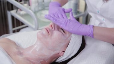Kadın güzellik uzmanı kadın bir hastanın yüzüne krem sürüyor. Yüz masajı.