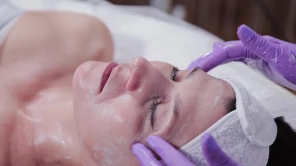 Femme esthéticienne faisant massage facial à la jeune femme. — Video