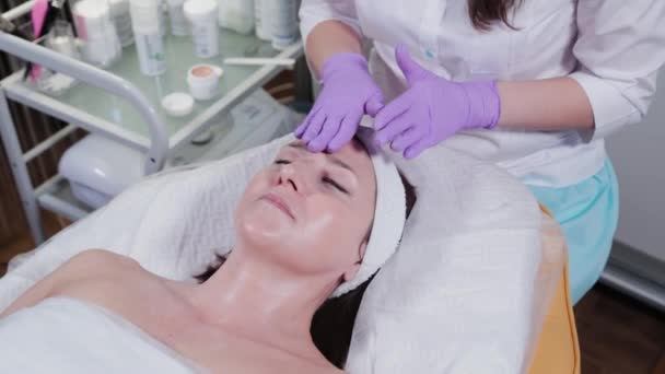 Femme cosmétologue massages femmes visage avec crème. — Video
