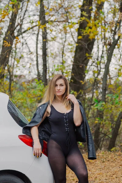 Beautiful woman by the car in the forest. — Stock Photo, Image