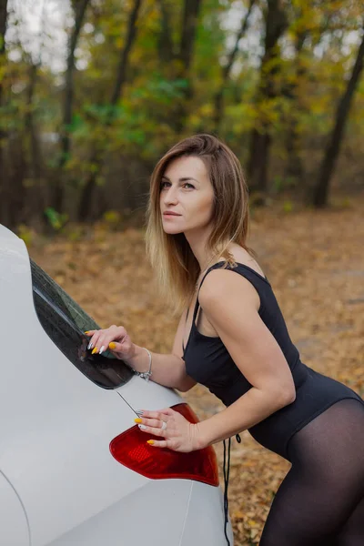 Beautiful woman by the car in the forest. — Stock Photo, Image