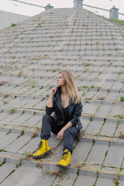 Mulher bonita senta-se em estruturas de concreto em tempo nublado. — Fotografia de Stock