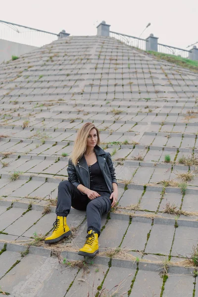 Mulher bonita senta-se em estruturas de concreto em tempo nublado. — Fotografia de Stock