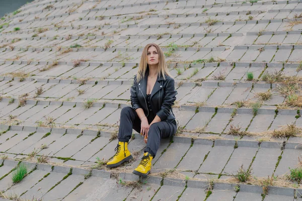 Mulher bonita senta-se em estruturas de concreto em tempo nublado. — Fotografia de Stock