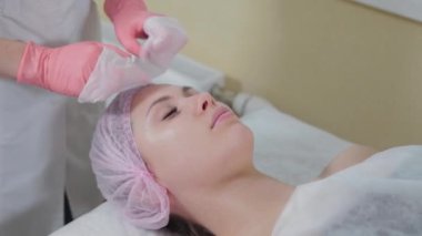 Profesyonel güzellik uzmanı kadın peçetelerle yüz yüze yıkanır..