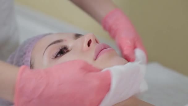 Esthéticienne professionnelle lave visage à client avec des serviettes. — Video