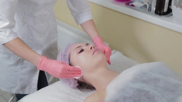 Cosmetologists mãos limpando sobrancelhas usando almofadas de algodão. Esteticista esfrega sobrancelhas clientes com uma almofada de algodão. Esteticista de luvas está fazendo maquiagem permanente para a menina. Correção da sobrancelha. — Vídeo de Stock