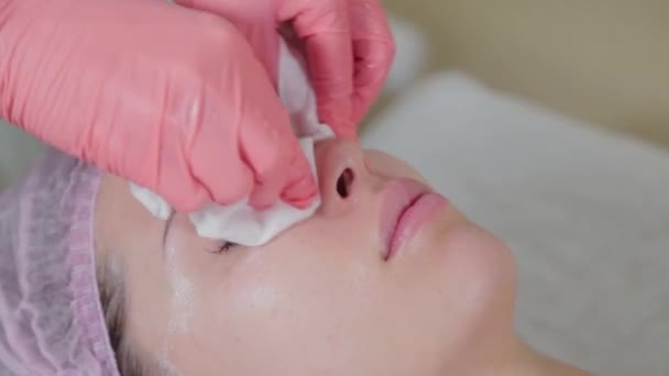 Esthéticienne professionnelle lave visage à client avec des serviettes. — Video