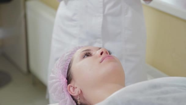 Professionele schoonheidsspecialiste vrouw aanbrengen masker op gezicht met borstel naar klant. — Stockvideo