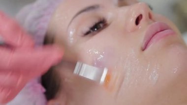 Profesyonel güzellik uzmanı kadın müşteriye fırçayla maske takıyor..