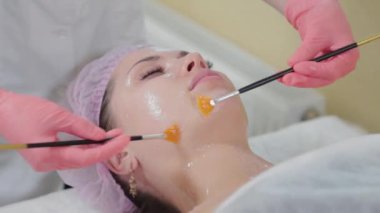 Kadın güzellik uzmanı fırçalarla masaj yapıyor..