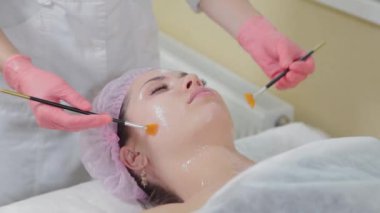 Kadın güzellik uzmanı fırçalarla masaj yapıyor..