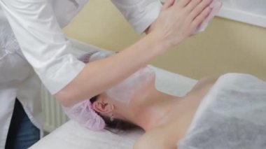 Genç bir kadın için miyoplastik boyun masajı yapan masajcı doktor, yakın çekim görüntüsü. Kozmetoloji kliniğinde güzellik spa prosedürü. Doktor, genç bir kızın boynunu okşayıp okşuyor..