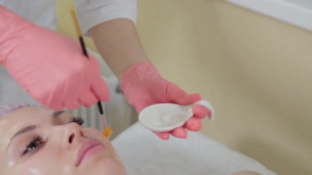 Estetista professionista donna applicare maschera sul viso con pennello al cliente. — Video Stock