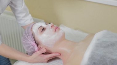 Genç bir kadın için miyoplastik boyun masajı yapan masajcı doktor, yakın çekim görüntüsü. Kozmetoloji kliniğinde güzellik spa prosedürü. Doktor, genç bir kızın boynunu okşayıp okşuyor..