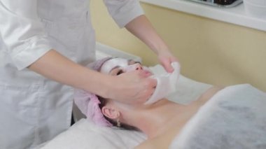 Profesyonel güzellik uzmanı kadın peçetelerle yüz yüze yıkanır..