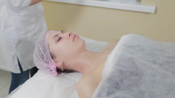 Professionell kosmetolog gnider flytande tvål på en kvinnas ansikte. — Stockvideo