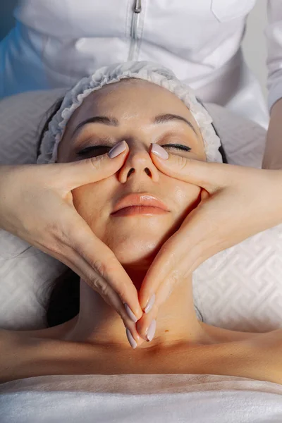 Professionelle Kosmetikerin Frau massiert Gesicht zu Client. — Stockfoto