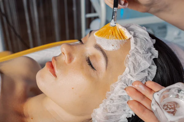 Profesyonel güzellik uzmanı kadın müşterilerinin yüzüne fırçayla maske takıyor. — Stok fotoğraf