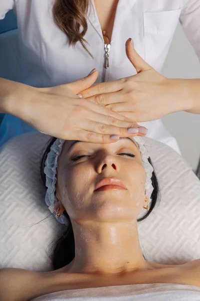 Professional beautician woman massaging face to client. Stok Gambar