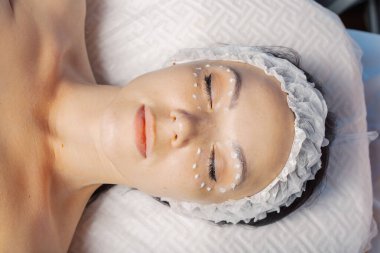 Yüzünde krem maske olan güzel genç bir kadın..