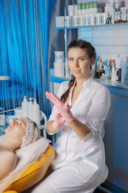 Profesyonel bir güzellik uzmanı estetik ameliyattan önce lastik eldiven giyer..