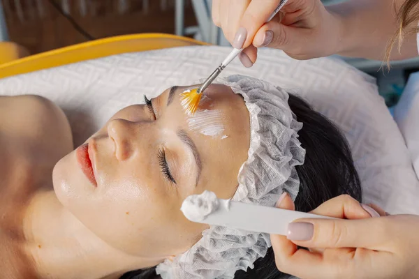 Professional beautician woman applies mask with brush to clients face. — Φωτογραφία Αρχείου