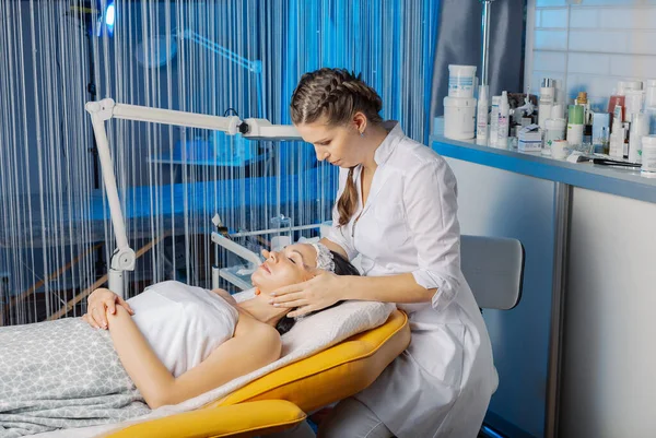 Esteticista profesional hace un masaje facial a una mujer. — Foto de Stock