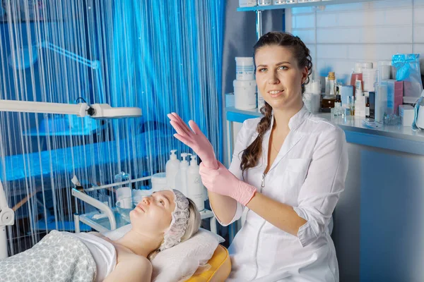 Un esteticista profesional se pone guantes de goma antes de un procedimiento cosmético. — Foto de Stock