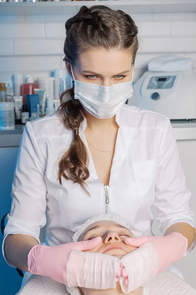 Professional beautician woman washes the clients face with napkins. — Zdjęcie stockowe