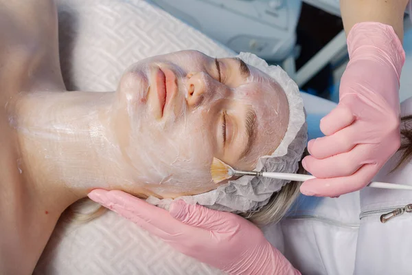 プロの美容師の女性は、クライアントの顔にブラシでマスクを適用します. — ストック写真