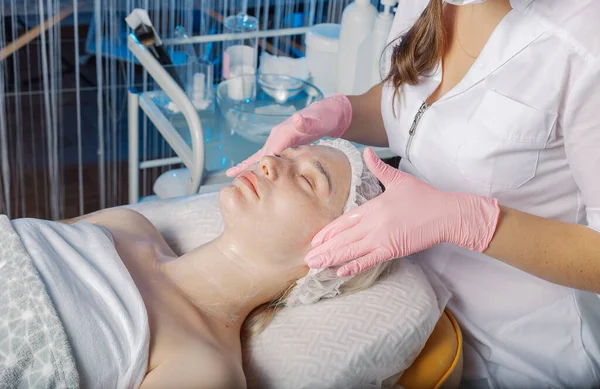 Professional beautician makes a facial massage to a woman. — Zdjęcie stockowe
