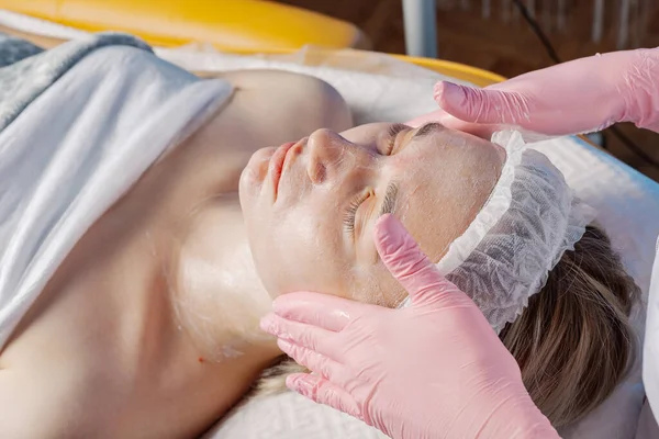 Professional beautician makes a facial massage to a woman. — Stockfoto